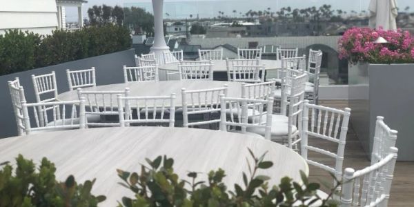 Empty white tables and chairs on a rooftop terrace.