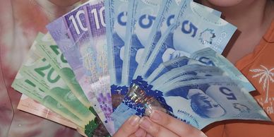 Person holding various denominations of Canadian banknotes.