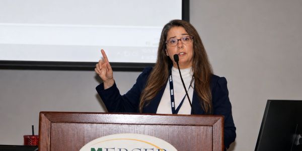 Woman giving a presentation at a podium with a microphone.