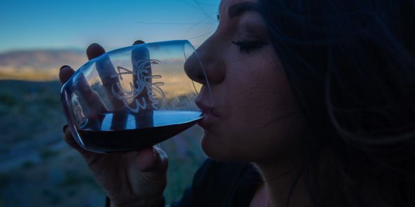 Young woman sipping Bitter Creek Winery red wine from Cellar 433 glass-mountains