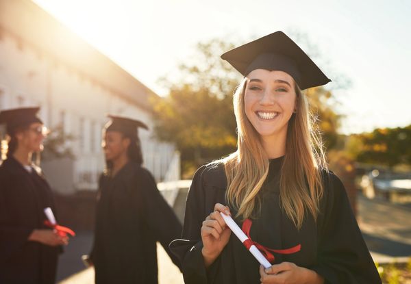 Girl in graduation uniform, holding diploma, smiling about her high ACT scores. Walker Prep Reviews.