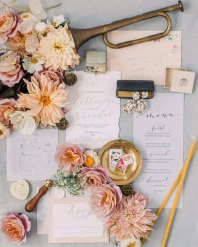 Wedding invitation set with flowers, vintage trumpet, and jewelry.