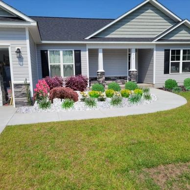 Neat front yard with colorful plants and a curved concrete path.