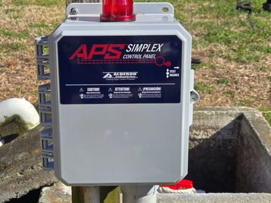 Outdoor APS Simplex control panel with warning labels and a red alert light.