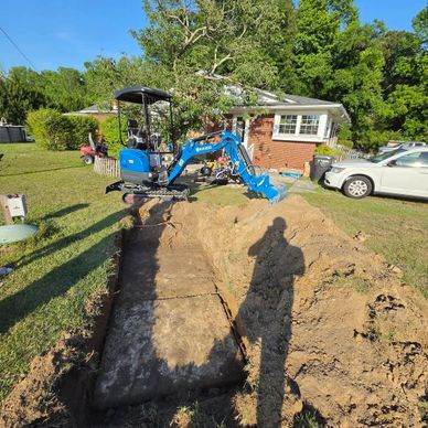 Mini excavator digging a trench in a residential yard.