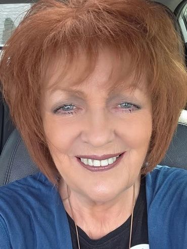 Smiling woman with red hair wearing an 'I Voted' sticker.