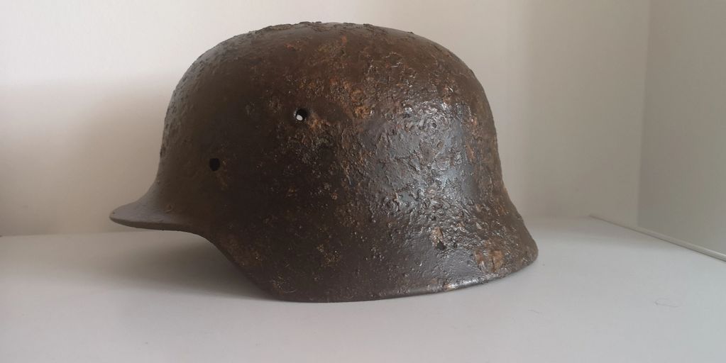 Rusty, old military helmet with worn texture and holes.