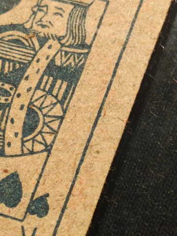 Close-up of a worn King of Spades playing card on a textured surface.