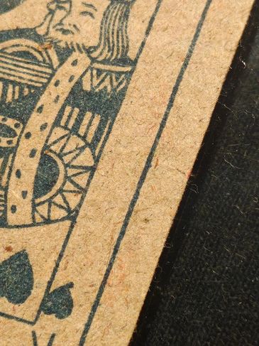 Close-up of a worn King of Spades playing card corner.