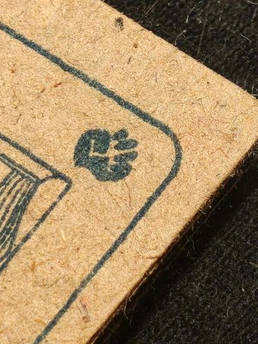 Close-up of a worn playing card corner with a small black heart symbol.