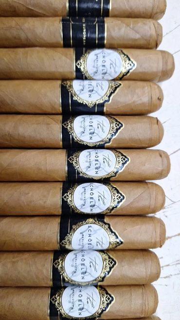 Close-up of neatly arranged Schoelen cigars with elegant black and gold bands.
