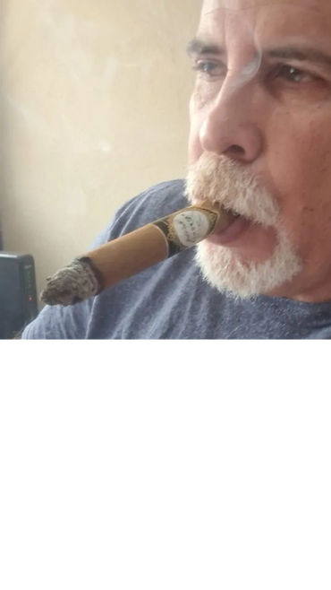 Man with gray hair smoking a cigar indoors.