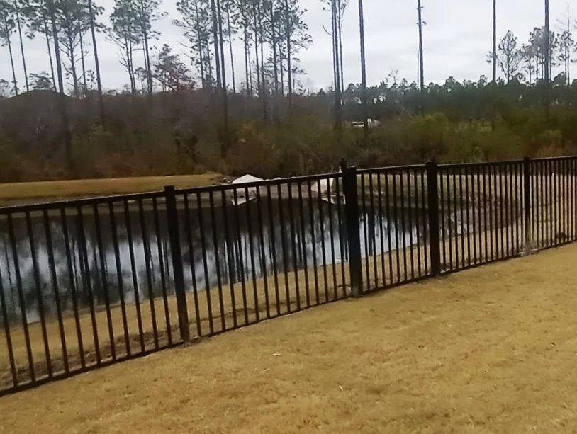 Black aluminum fence with a gate surrounding back yard in Bay County FL