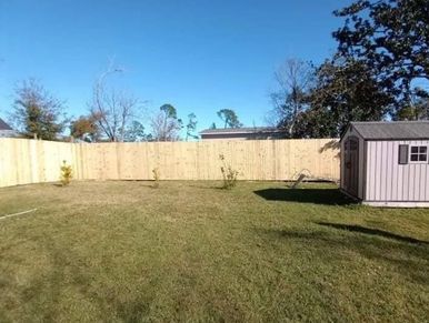 High wood fence in back yard with shed in Lynn Haven, FL