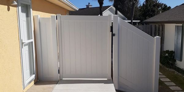 White vinyl privacy fence gate on concrete entrance-way to home. Gate side-panel was customized.