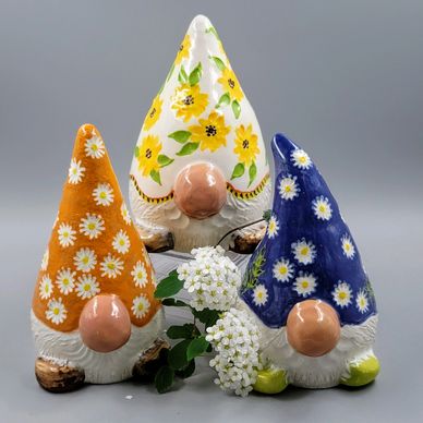 Three colorful floral-patterned garden gnome statues with white beards and large noses.