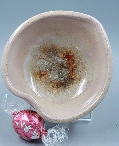 Cracked ceramic bowl with discoloration next to a wrapped pink candy.