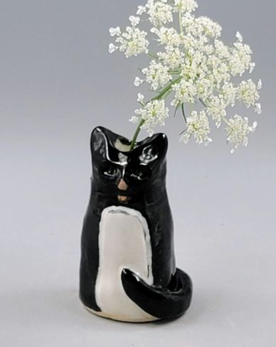 Black and white cat-shaped vase with white flowers.