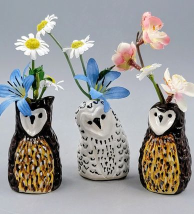 Three owl-shaped ceramic vases with flowers.