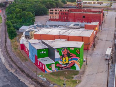 Colorful mural artwork on building near train tracks.