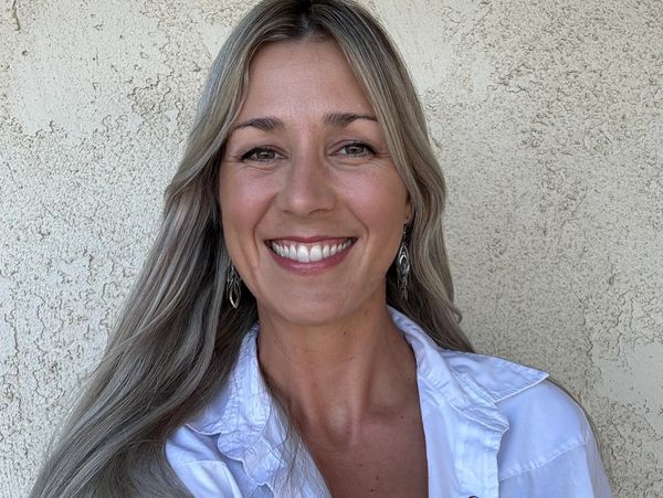 Smiling woman with long blonde hair and white shirt.