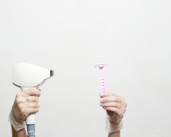 Hand holding a laser hair removal tool in one hand and a Razer in the other hand.