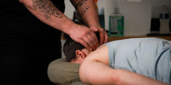 Person receiving a head massage from a tattooed therapist.