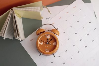Orange alarm clock and calendar on a desk with color swatches.