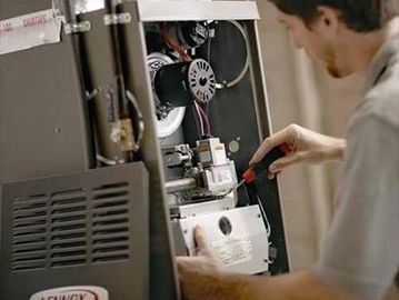 A technician repairs a Lennox furnace using a screwdriver.