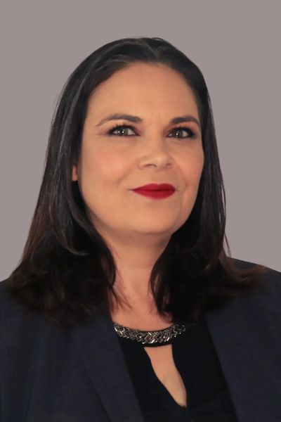 Professional woman with dark hair and red lipstick against a plain background.