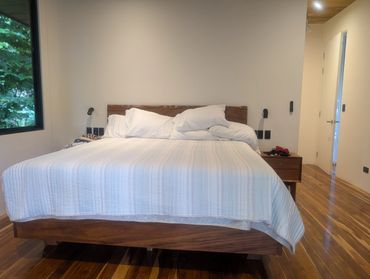 Modern bedroom with wooden furniture and white bedding.