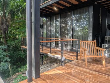 Wooden deck with a chair overlooking a lush green forest.