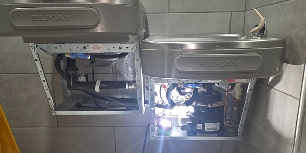 Two Elkay water fountains with exposed plumbing and wiring underneath.