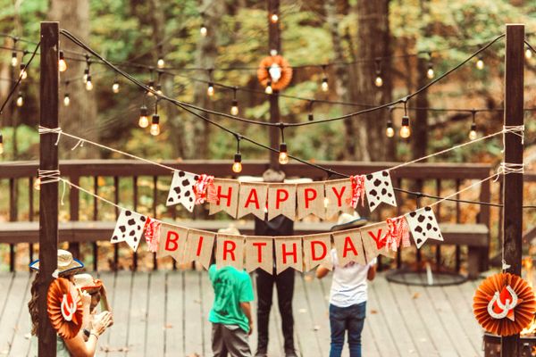 Outdoor birthday party with rustic decorations and string lights.