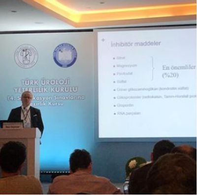 A speaker presenting at a Turkish urology proficiency course with a slide on inhibitor agents.