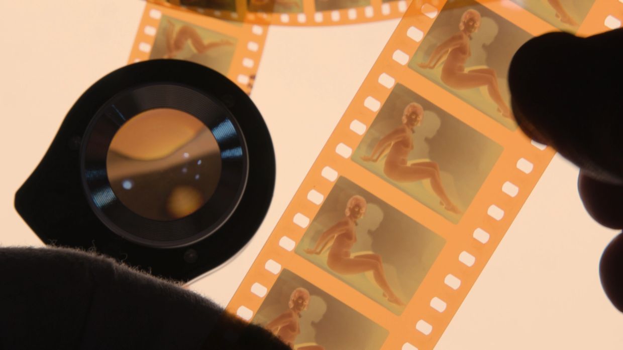 Photographic film strip showing a seated woman, viewed with a magnifier.