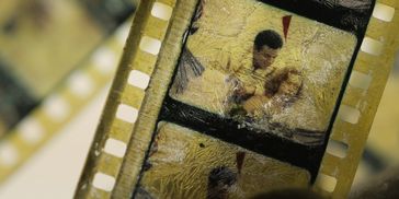 Old damaged film strip with people visible in frames.