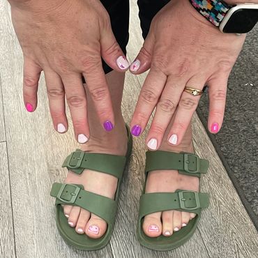 A colorful manicure and pedicure with pink, purple, and white nail polish.
