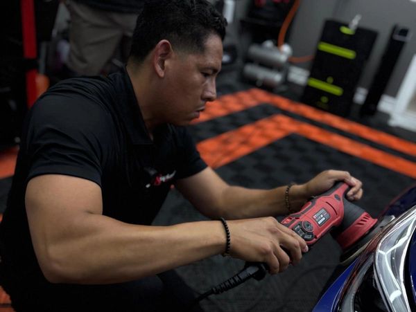 Man polishing a car with a power buffer.