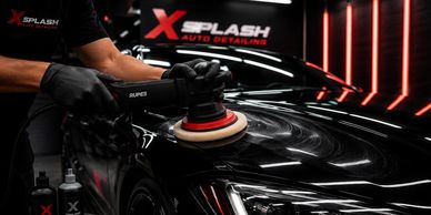A person polishing a sleek black car with a buffer.