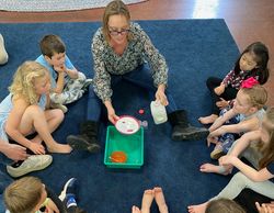 teacher showing students that are sitting in a circle a science experience