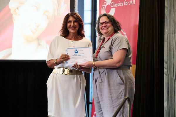 Two women smiling while holding a certificate at an event.
