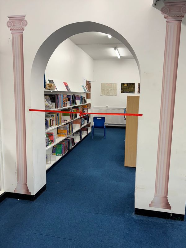 Library aisle with hanging red tape and blue chair.