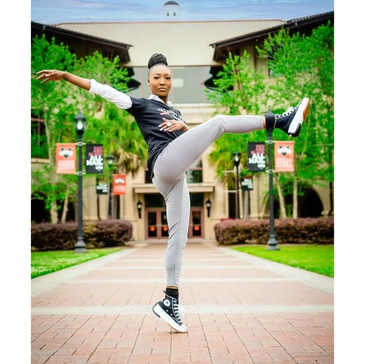 a girl doing a kick dance in front of a building