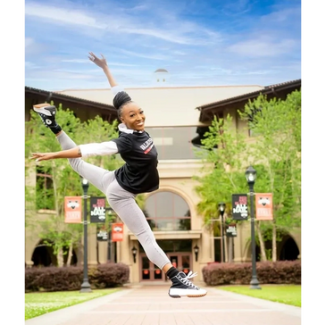 a dancer jumping in front of a building