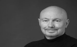 Black and white portrait of a smiling bald man.