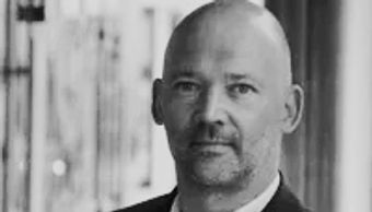 Black and white portrait of a bald man with a trimmed beard.