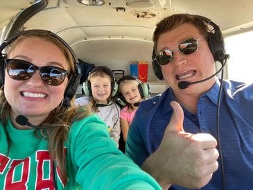 Family selfie inside a small airplane with headsets on.