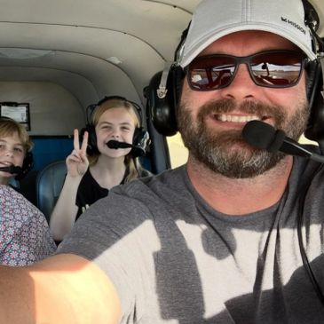 Man and two kids flying in a small plane.