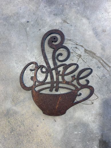 Rusty metal art piece on concrete floor with intricate swirls.